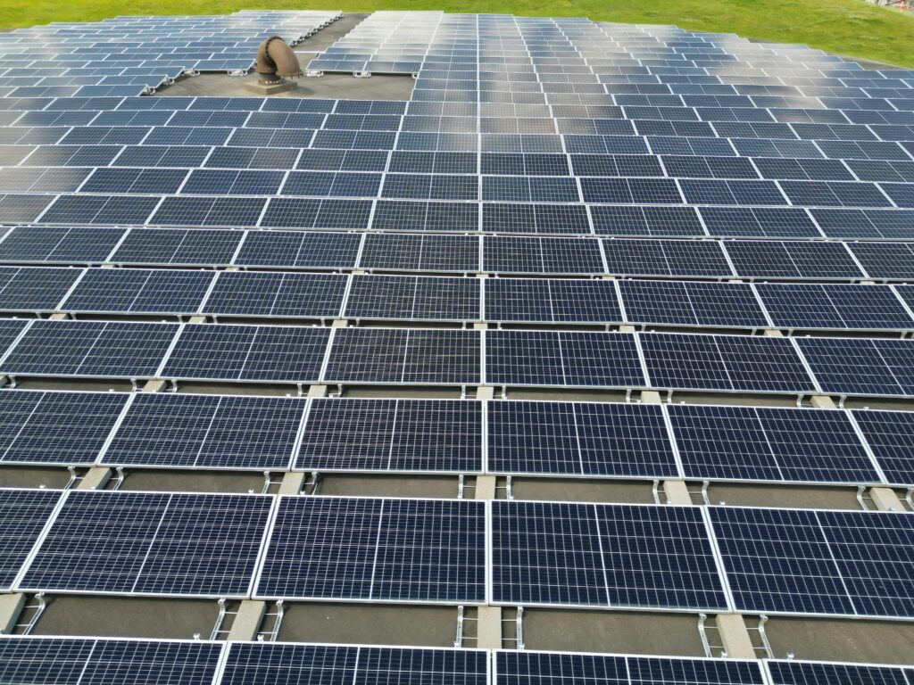 A large solar panel array on a sunny day in an open green field.