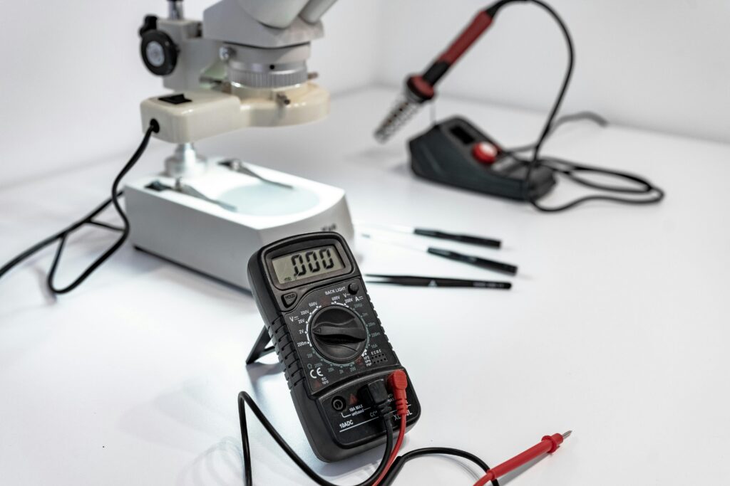 Electronics workbench with multimeter, microscope, and soldering iron.